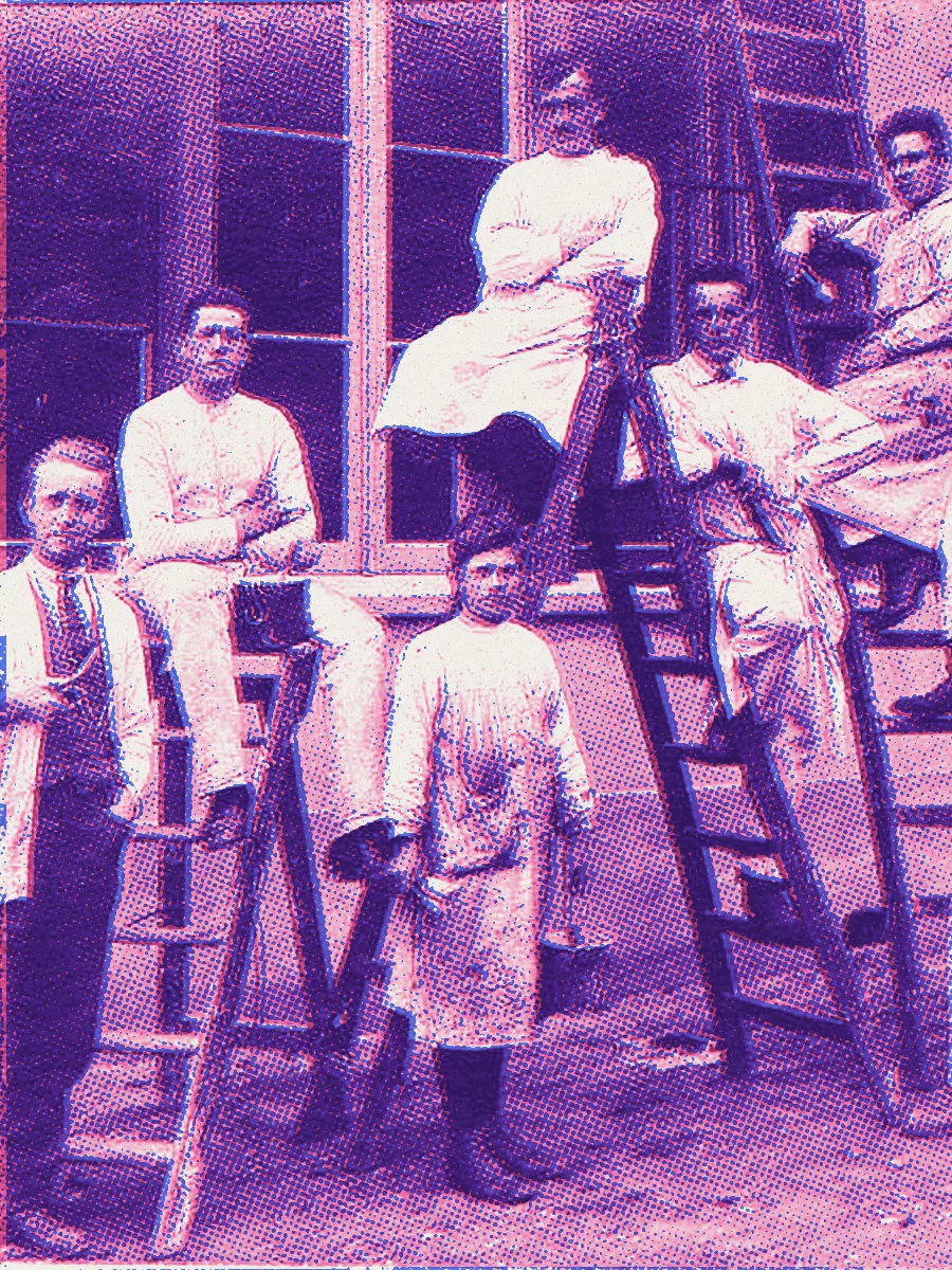 Schilders van het bedrijf Hendrixen poseren met ladders en verfemmers voor een gevel, historische foto