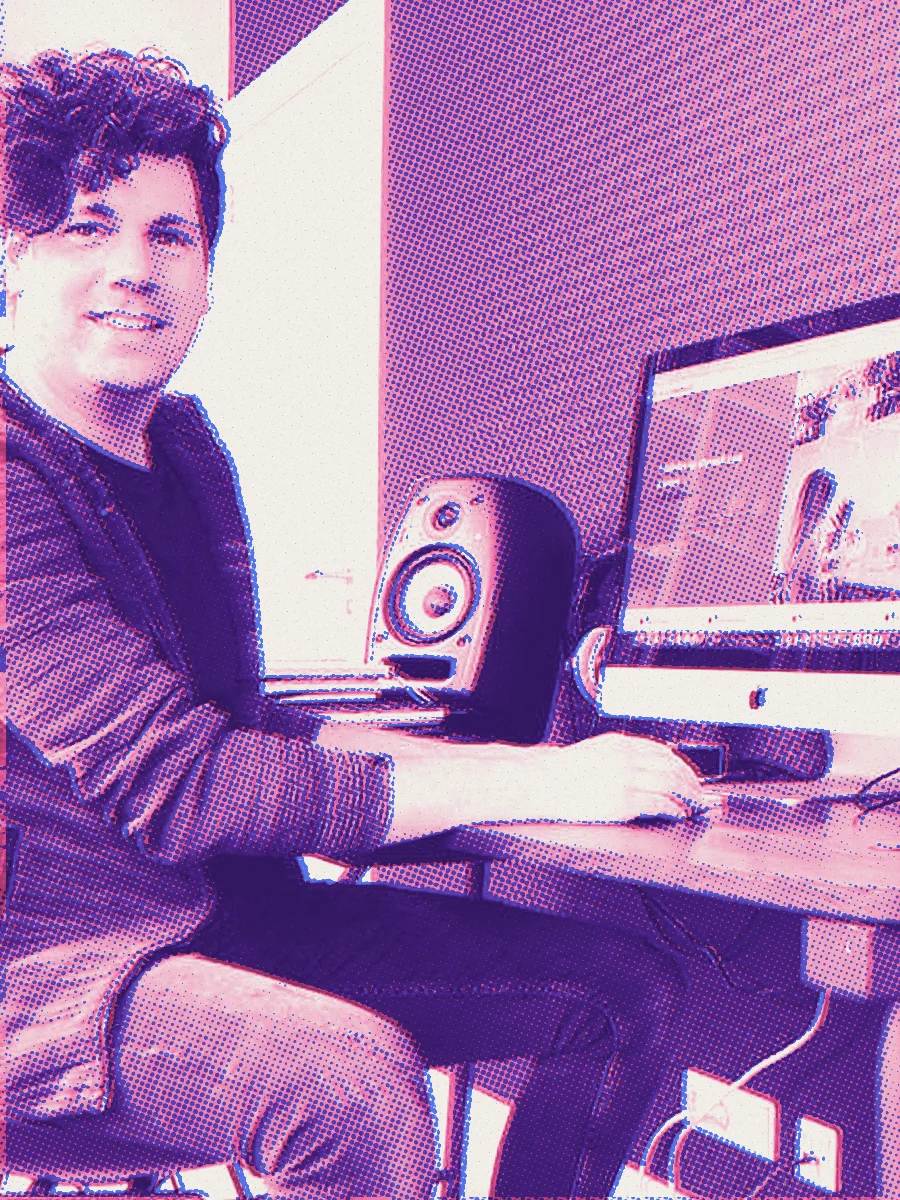 Wouter Hendrixen aan zijn bureau met een iMac, studiomonitors en een gitaar